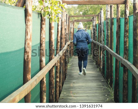 Unidentified woman walking away leaving the game reserve watch post or watch hole in Hluhluwe game reserve, South Africa. Walk way is covered with green nylon as camouflage.