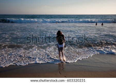 Unidentified woman walking into the ocean on Santa Monica Beach, California, USA