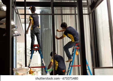 Unidentified Worker Applying Tinted Layer On Glass Window In Summer