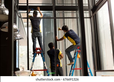 Unidentified Worker Applying Tinted Layer On Glass Window In Summer