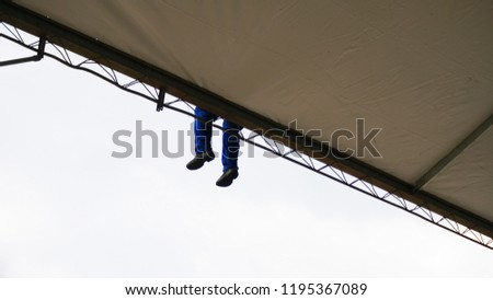 Unidentified worker is sitting on top of a construction site. Cloudy day.