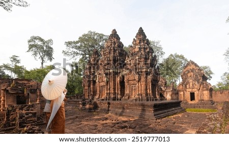 Unidentified young couple orange  traditional ceremonial wedding Khmer clothing at the ancient Banteay Srei Hindu temple dedicated to Shiva in the jungle of the Angkor wat complex area of Cambodia.
