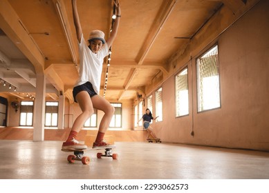 Unidentified young woman in casual sports clothing learning and practicing skateboarding while trying to balance with arms extended on artificial indoor small slide in skating studio during daytime - Powered by Shutterstock