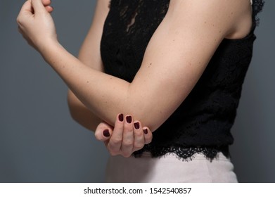 An Unidentified Young Woman Shows Strong Biceps On A Gray Background Depicting Physical And Moral Strength. The Concept Of A Strong And Independent Woman