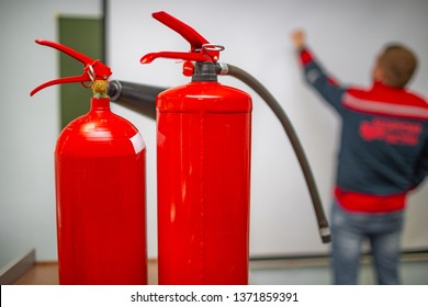 Uniformed Fireman Gives A Lecture Or Instruction On Fire Safety. The Instructor Teaches The Use Of Fire Extinguisher