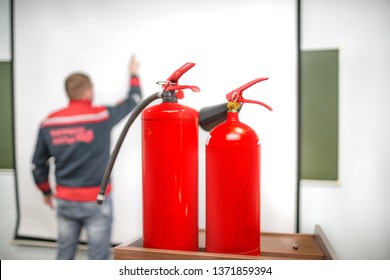 Uniformed Fireman Gives A Lecture Or Instruction On Fire Safety. The Instructor Teaches The Use Of Fire Extinguisher