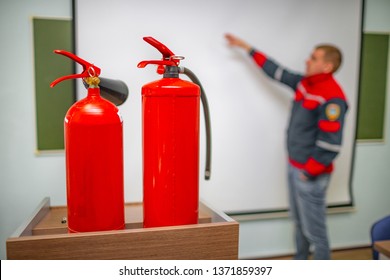 Uniformed Fireman Gives A Lecture Or Instruction On Fire Safety. The Instructor Teaches The Use Of Fire Extinguisher