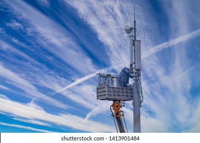 Uniformed Worker Repairing Cell Tower Against Sky