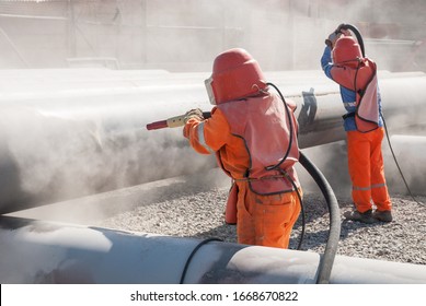 uniformed workers performing sandblasting process