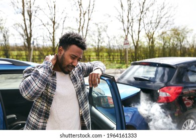 Uninsured male driver rubbing neck in pain from whiplash injury standing by damaged car after traffic accident for which he is to blame - Shutterstock ID 1964161333