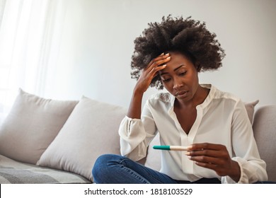 Unintended Pregnancy. Depressed African American Woman Upset With Positive Test Results, Sitting On Couch At Home With Sad Face Expression. Medical Test And Black Woman Feeling Sad