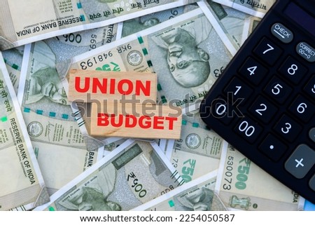 Union budget 2023 word on wooden block with Indian currency banknotes and calculator