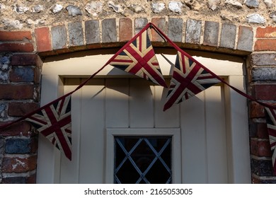Union Jack flag bunting above a traditional downland cottage door in an English village