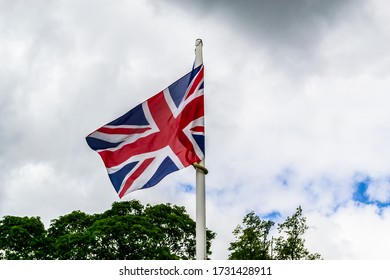 Union Jack flag wrapped around a pole in a park in England - Shutterstock ID 1731428911
