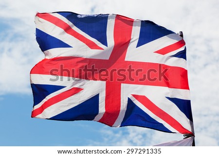 The Union Jack, the national flag of the United Kingdom waving on wind against blue sky