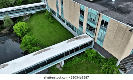 The unique adaptation of elements that act as a means of static transportation to connect two separate occupiable buildings for the means of implementing and progressing the societal development of students.