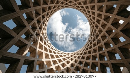 A unique architectural design featuring a geometric wooden lattice structure with a view of the sky and clouds through the opening.
