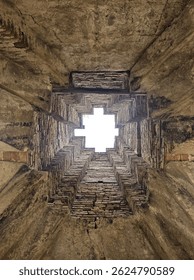 a unique architectural structure viewed from below, revealing a brick-lined, cross-shaped skylight.