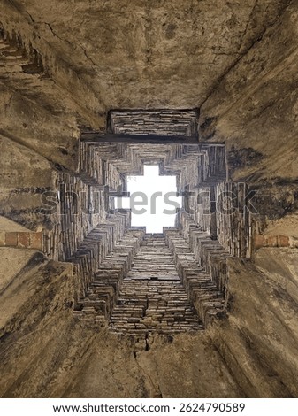 a unique architectural structure viewed from below, revealing a brick-lined, cross-shaped skylight.