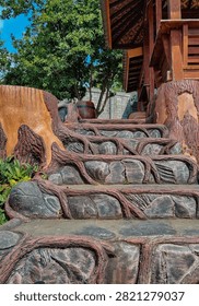Unique artificial tree root concrete staircase in a tropical garden leading to a traditional wooden gazebo