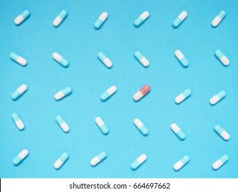 Unique Brown Capsule Among Many Blue And White Capsule On Blue Background. Creative Idea For Uniqueness, Innovation, Different Thinking, Individuality, Contrast And Pharmaceutical Concept.