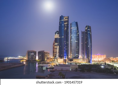 A unique and different perspective of skyscraper towers and cityscape skyline of Abu Dhabi, UAE at night under moonlight.
