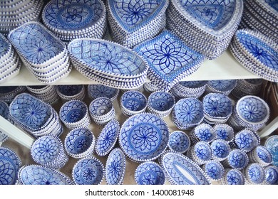 Unique handmade tracery oriental pottery crockery plates different forms made of natural clay painted to a traditional blue ornament, glazed on a market shelf set in a row diagonal top view close up - Powered by Shutterstock