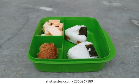 A unique and interesting school lunch menu with a menu of rice, biscuits and crispy fried chicken in a green container - Powered by Shutterstock