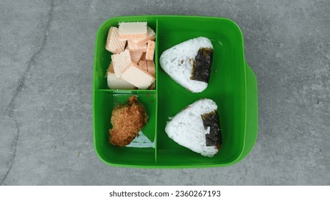 A unique and interesting school lunch menu with a menu of rice, biscuits and crispy fried chicken in a green container - Powered by Shutterstock