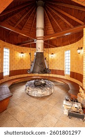 Unique interior featuring a round brick room with a central fireplace, wooden benches, and ambient lighting. Rustic and cozy atmosphere.