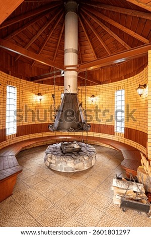 Unique interior featuring a round brick room with a central fireplace, wooden benches, and ambient lighting. Rustic and cozy atmosphere.