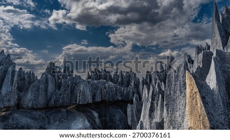 Unique karst rocks. Sharp spiky peaks against a background of blue sky and clouds. Steep furrowed slopes. Madagascar. Tsingy De Bemaraha 