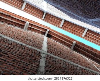 A unique low-angle view of bats hanging upside down beneath the roof tiles of a residential house. This wildlife image captures the natural roosting behavior of bats in an urban environment, highlighting their role in biodiversity, nocturnal ecosystems, and coexistence with humans.