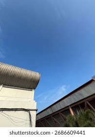Unique Low-Angle View of Modern Architecture with Curved Roof and Clear Blue Sky on a Sunny Day.