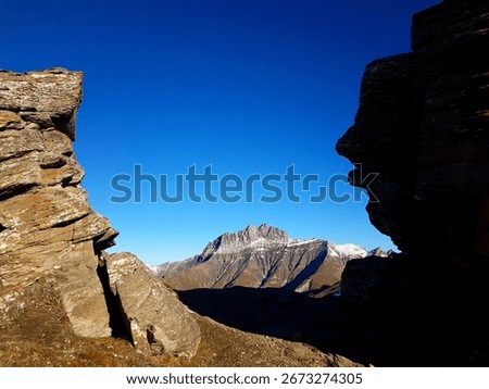 Unique mountain view of the Stammerspitze through two large boulders in clear autumn light, Engadine Valley, Switzerland