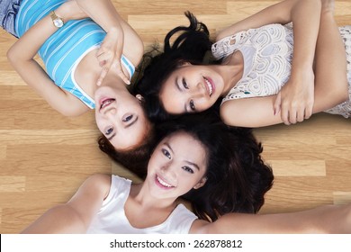 Unique Perspective Of Three Teenage Girls Lying Down On The Wooden Floor And Taking Self Photo Together