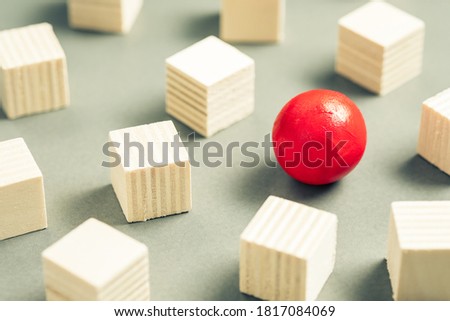 Unique red sphere in a group of sqaure cubes, small wooden objects for design and carpentry work, different and unique, positioning for advertising and business concept