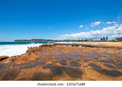 Unique rock pattern on Australian beach with vivid blue sky and sandy coastline