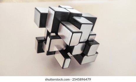 A unique rubik's puzzle cube in silver and black, on a white background