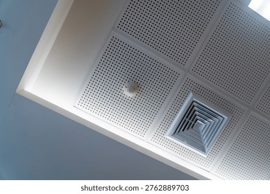 A unique upward view of a ceiling featuring an air vent and smoke detector, showcasing the clean lines and modern design of interior architecture. Ideal for interior design projects.