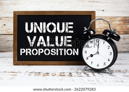 Unique Value Proposition text message and alarm clock on wooden background