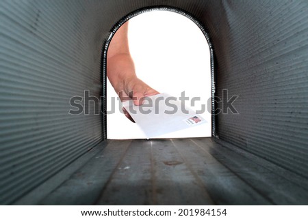 A Unique view of someone getting or placing mail in a mail box, shot from the Inside Out. 