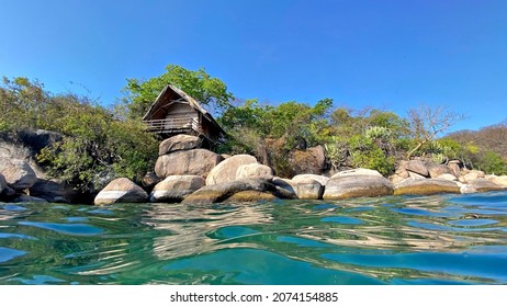 A unique water view of quaint, rustic holiday chalets or huts on a beautiful island resort in Lake Malawi.