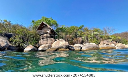 A unique water view of quaint, rustic holiday chalets or huts on a beautiful island resort in Lake Malawi.