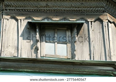 Unique window framed by weathered wood tells stories of a bygone era.