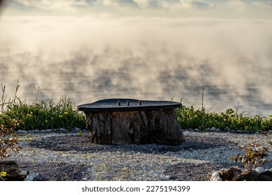 Uniquely crafted open-air dining table made outo tree stump. Foggy morning.
