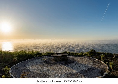 Uniquely crafted open-air dining table made outo tree stump. Foggy morning. Sunrise.