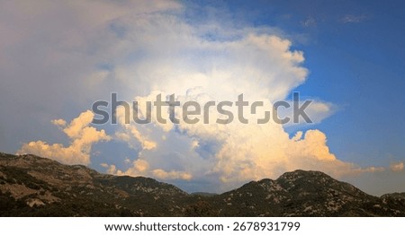 Uniquely shaped vertical cloud lingering over the green mountaintop