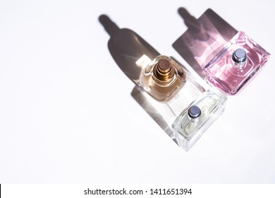 Unisex Perfume Bottles On White Background With Long Hard Shadows.