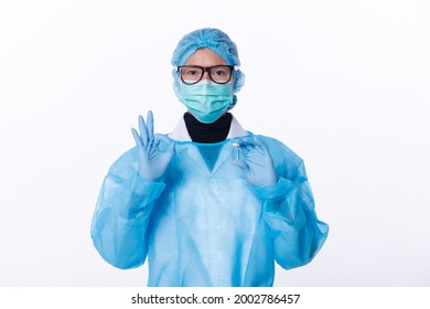 Unisex Scientist Wear Full PPE Suit, Glove, Helmet. Medical Doctor Shows Victory Okay Finger Sign With Vaccine Bottle Dose. Isolated White Background Copy Space